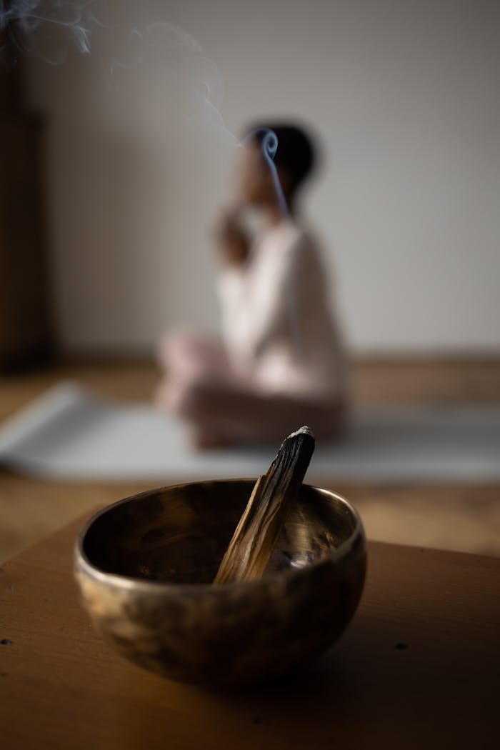 A serene moment of mindfulness featuring incense in a singing bowl during yoga practice.